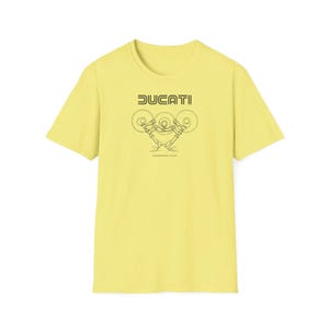 Puede incluir: Camiseta amarillo claro con la palabra "DUCATI" en negro, encima de un gráfico negro de un motor de motocicleta. La camiseta está hecha de un material suave y tiene mangas cortas.