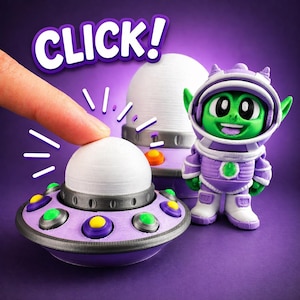 May include: A purple and gray toy spaceship with a white dome is being pressed by a finger. The word "CLICK!" is above the spaceship. A green alien astronaut figure in a purple spacesuit stands nearby. The background is purple.