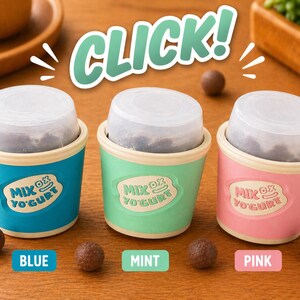May include: Three colorful yogurt cups, blue, mint, and pink, each with a clear lid and filled with a dark substance. The cups have the text "Mix Ox Yogurt" and are surrounded by chocolate-covered candies. The word "CLICK!" is in the background.