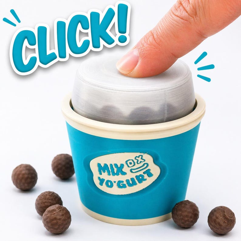 May include: A blue and white container with the text "MIX YO'GURT" is shown with a finger pressing down on the lid. The word "CLICK!" is in a bubble above the container. Several brown, spherical objects are scattered around the container.