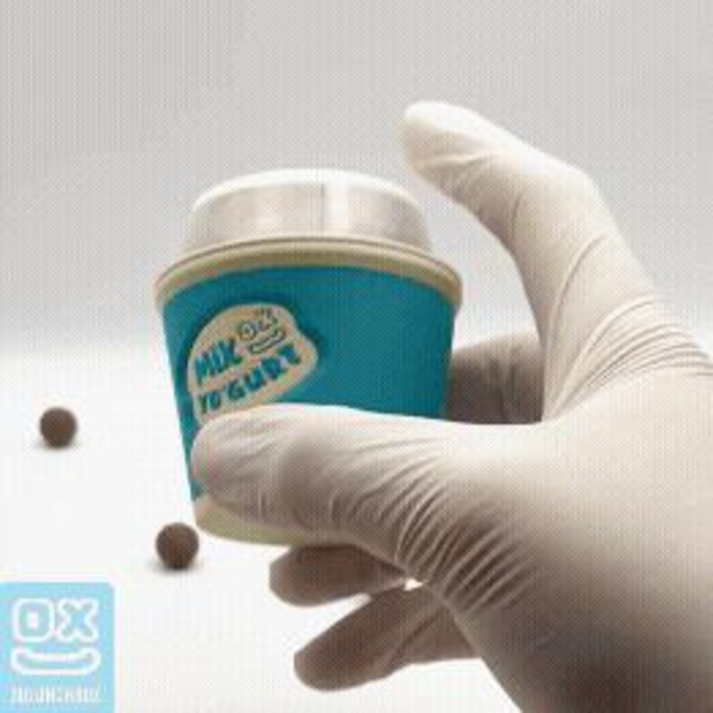 May include: A teal and white yogurt container with the text "Milk Yogurt" and a cartoon character. The container is held by a gloved hand. Three small, round, brown objects are scattered nearby.