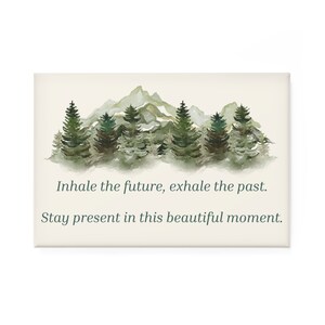 May include: A watercolor painting of a mountain range with a forest of pine trees in the foreground. The text "Inhale the future, exhale the past. Stay present in this beautiful moment." is printed below the image.
