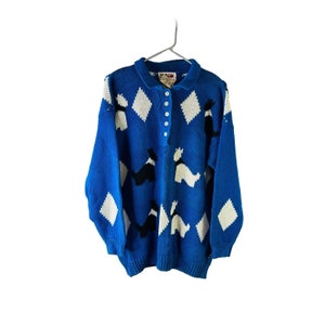 May include: A blue knitted sweater with a white and black diamond pattern and black and white dog silhouettes. The sweater has a button-up collar.