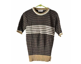 May include: Short-sleeved knit top with horizontal stripes in shades of brown, white, and tan. The top has a ribbed texture and a crew neck with a contrasting white and tan collar. The sleeves and hem are finished with a tan trim. The top is hanging on a green hanger.