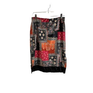 May include: A black skirt with a patchwork design featuring red, orange, and gray paisley patterns. The skirt has a black velvet trim.