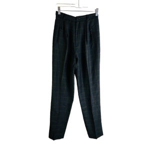 May include: Dark teal plaid trousers hanging on a metal hanger. The high-waisted trousers have a classic fit with pleats at the waist and a straight leg. The plaid pattern features thin lines of brown and teal, creating a subtle grid design.