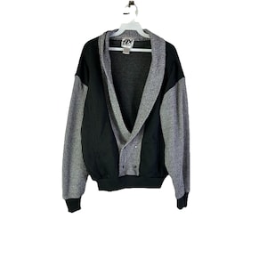 May include: A vintage black and gray jacket with a shawl collar and button closure. The sleeves are gray with vertical stripes, and the body is black. The jacket is hanging on a white hanger.