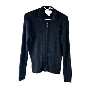 May include: A black zippered cardigan with a beaded collar. The cardigan is made of a soft, ribbed knit fabric.