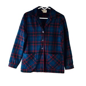 May include: A blue, red, and black plaid jacket with a collared neckline, two front pockets, and button closures. The jacket is hanging on a white hanger against a white background. The jacket's plaid pattern is a classic design.