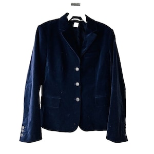 Puede incluir: Una chaqueta de terciopelo azul oscuro con cierre de tres botones y dos bolsillos.