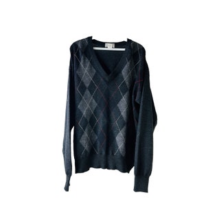 May include: A black and grey argyle sweater with a v-neck.
