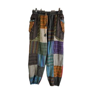 May include: Patchwork pants with a colorful striped pattern in shades of brown, green, blue, orange, and purple. The pants have an elastic waistband and a drawstring.