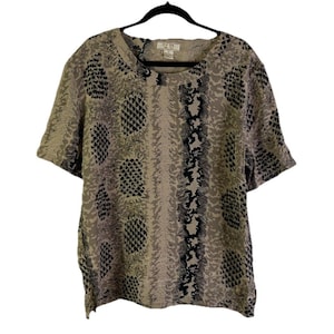 May include: A short-sleeved blouse with a snakeskin pattern in shades of beige, gray, and black. The top is hanging on a black hanger. The blouse has a round neckline and a loose fit.