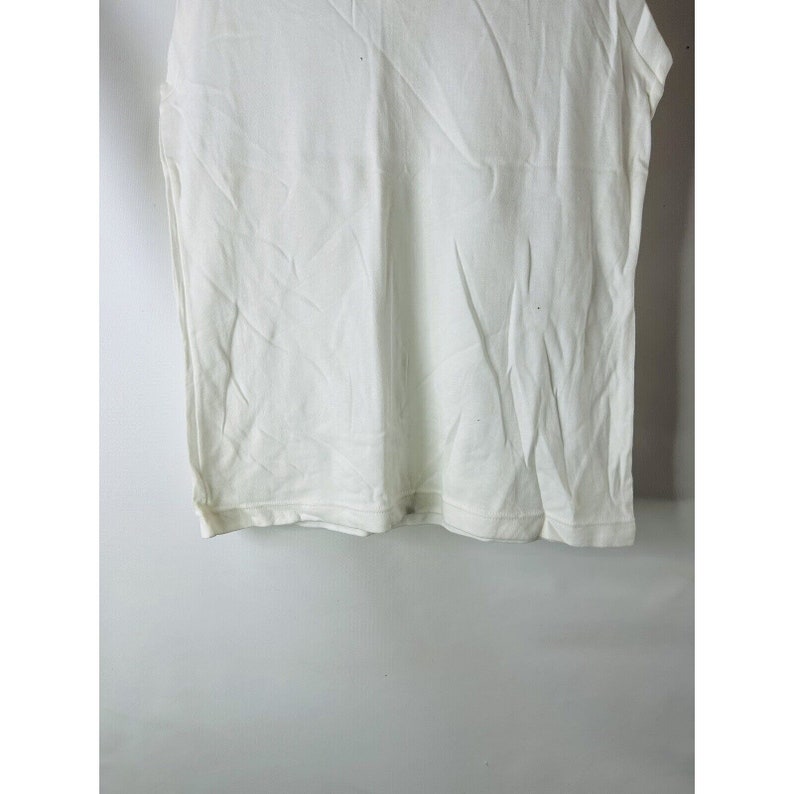 May include: A white sleeveless shirt with a crew neck.