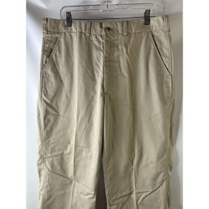 May include: A pair of beige casual trousers with a button fly and two front pockets.