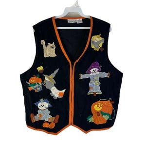 May include: Black Halloween vest with orange trim and various appliqued designs. The appliqués include a cat, scarecrows, pumpkins, and a witch on a broom. The vest is sleeveless and has a V-neck.