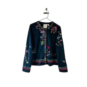 May include: A dark blue embroidered jacket with colorful floral designs. The jacket has a button closure and a striped detail down the front.
