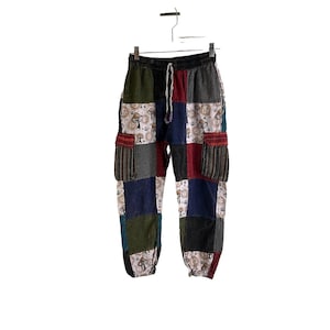 May include: Patchwork pants with a drawstring waist and multiple pockets. The pants are made of a variety of fabrics in different colors and patterns, including blue, green, red, and white. The fabric features a mushroom and peace sign design.