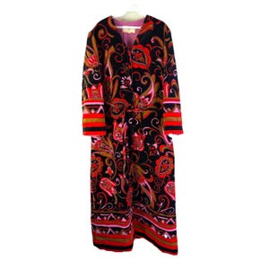 May include: A long, black robe with a vibrant floral pattern in red, gold, and pink. The robe features a matching belt, red trim on the sleeves, and a pink interior lining. The robe is hanging on a white hanger.