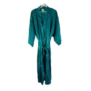 May include: Teal-colored satin robe with a subtle floral pattern. The robe features a shawl collar, long sleeves, and a matching tie belt. The fabric has a slight sheen, and the robe is hanging on a white hanger.