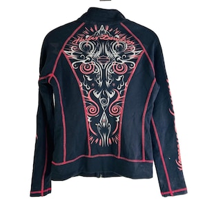 Könnte beinhalten: Schwarze Jacke mit Reißverschluss, roten Nähten und dekorativem Rückenteil. Der Rücken zeigt ein Harley-Davidson-Design in Rosa und Silber. Die Ärmel haben ebenfalls dekorative Elemente. Die Jacke hat einen durchgehenden Reißverschluss.