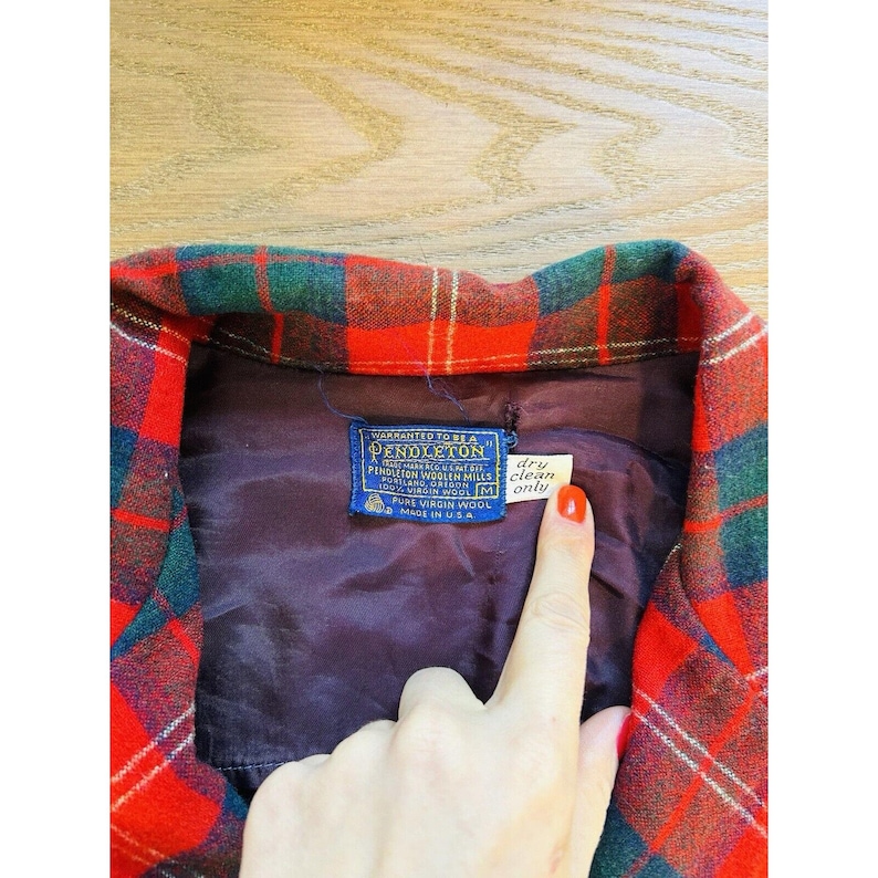 May include: Red and green plaid Pendleton wool shirt with a label that reads "WARRANTED TO BE A PENDLETON" and "100% VIRGIN WOOL" and "MADE IN U.S.A.". The label also has a handwritten note that says "dry clean only".