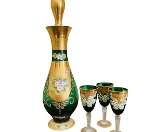 May include: A set of four green glass decanters with gold accents and floral designs. The decanters have a round body and a long, thin neck. The set includes a larger decanter and three smaller decanters.