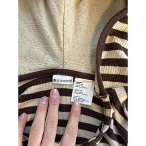Op de afbeelding: Bruin en beige gestreept hooded shirt met een "no boundaries" label. Het label zegt "Juniors L (11/13) 100% Katoen Gemaakt in Guatemala RN# 83019"