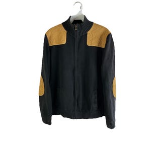 Könnte beinhalten: Ein schwarzer Reißverschluss-Pullover mit braunen Leder-Ellenbogen-Patches und Schulterakzenten.