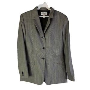 Puede incluir: Un blazer gris con un sutil patr&oacute;n de rayas verticales, con solapas y tres botones negros en la parte delantera. El blazer tiene mangas largas con tres botones en cada pu&ntilde;o. La marca "Pendleton" es visible.