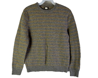 May include: Gray crew neck sweater with horizontal gold stripes. The sweater is made of a soft, textured material and has long sleeves. The sweater is hanging on a white hanger.