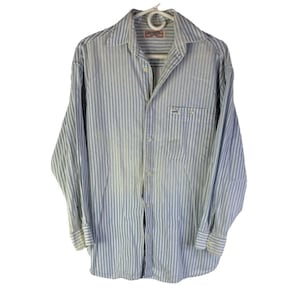 May include: A white ceramic mug with a black handle and the text "But First, Coffee" in a handwritten style. The mug is on a white surface. The mug is 4 inches tall.