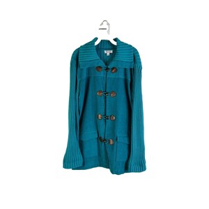 May include: Teal blue knitted cardigan with a large collar and brown toggle closures.