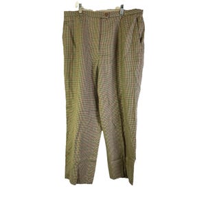 May include: Trousers in a tan and brown plaid pattern, suspended from a metal hanger. These trousers feature a button fastening and pockets. The fabric displays a small checkered design. A classic style.