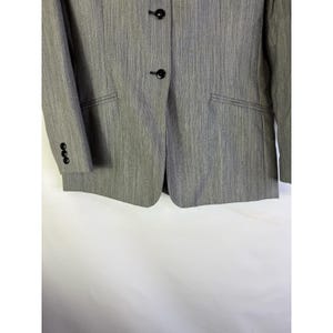 Puede incluir: Un blazer gris con un patr&oacute;n de rayas verticales texturizadas. El blazer tiene dos botones negros, un bolsillo y tres botones en la manga. La chaqueta es de estilo cl&aacute;sico.