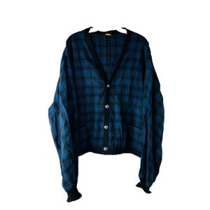 May include: A blue and black plaid cardigan with a v-neck and button closure. The cardigan has a ribbed knit collar, cuffs, and hem.