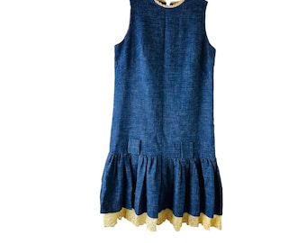 Puede incluir: Un vestido de mezclilla sin mangas con un dobladillo con volantes y un borde de encaje. El vestido es de color azul oscuro.