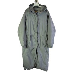 May include: A long, light gray winter coat with a hood. The coat has a button and snap closure, two front pockets, and ribbed cuffs. The coat is hanging on a white hanger.