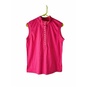 May include: A sleeveless pink shirt with a mock neck and a row of gold buttons down the front.