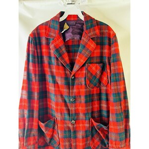 May include: A red, green, and white plaid blazer with a button closure and two pockets on the front.
