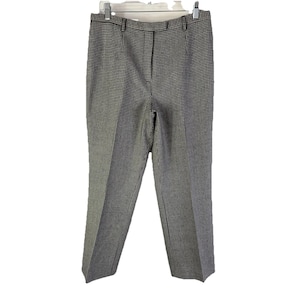 May include: A pair of black and white checkered trousers hanging on a white hanger. The pants have a classic, straight-leg design and a subtle pattern. The fabric appears to be a medium-weight material.