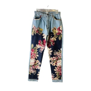 May include: Light blue denim jeans with floral fabric panels on the legs. The floral fabric is a dark blue background with pink, red, and yellow flowers.