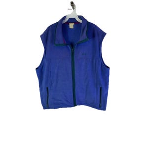 May include: A sleeveless, blue fleece vest with a full-length zipper and two side pockets. The vest has a green trim around the collar and zipper. The brand name "Jill Bean" is embroidered on the chest.