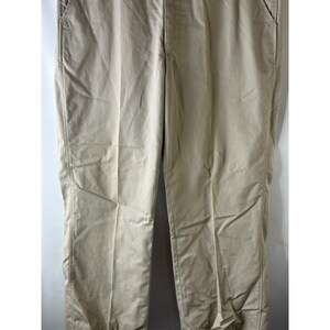 May include: A pair of beige casual trousers. The trousers have a straight leg and a relaxed fit.