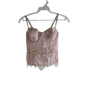 May include: A dusty rose lace corset top with a scalloped hem and a band of decorative circles around the waist.
