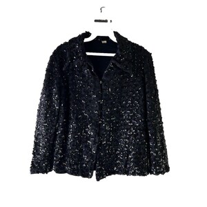 May include: A black sequined jacket with a button-up front closure. The jacket has a slightly oversized fit and a textured, sparkly finish.
