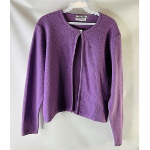 May include: A purple cardigan sweater with a single button closure. The sweater is made by Pendleton.