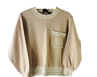 May include: A beige sweatshirt with a white and beige striped trim around the neck and bottom. The sweatshirt has a single pocket on the front with a white embroidered logo.