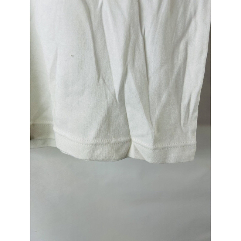 May include: Close-up of the bottom hem of a white t-shirt. The hem is stitched with a straight stitch.