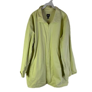 May include: A light green zip-up jacket with a collar, hanging on a white hanger. The jacket has a full-length zipper and long sleeves. The brand name "Eileen Fisher" is visible on the label.